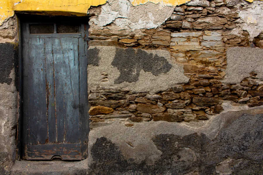 Blue-grey door with exposed schist wall, yellow lintel above