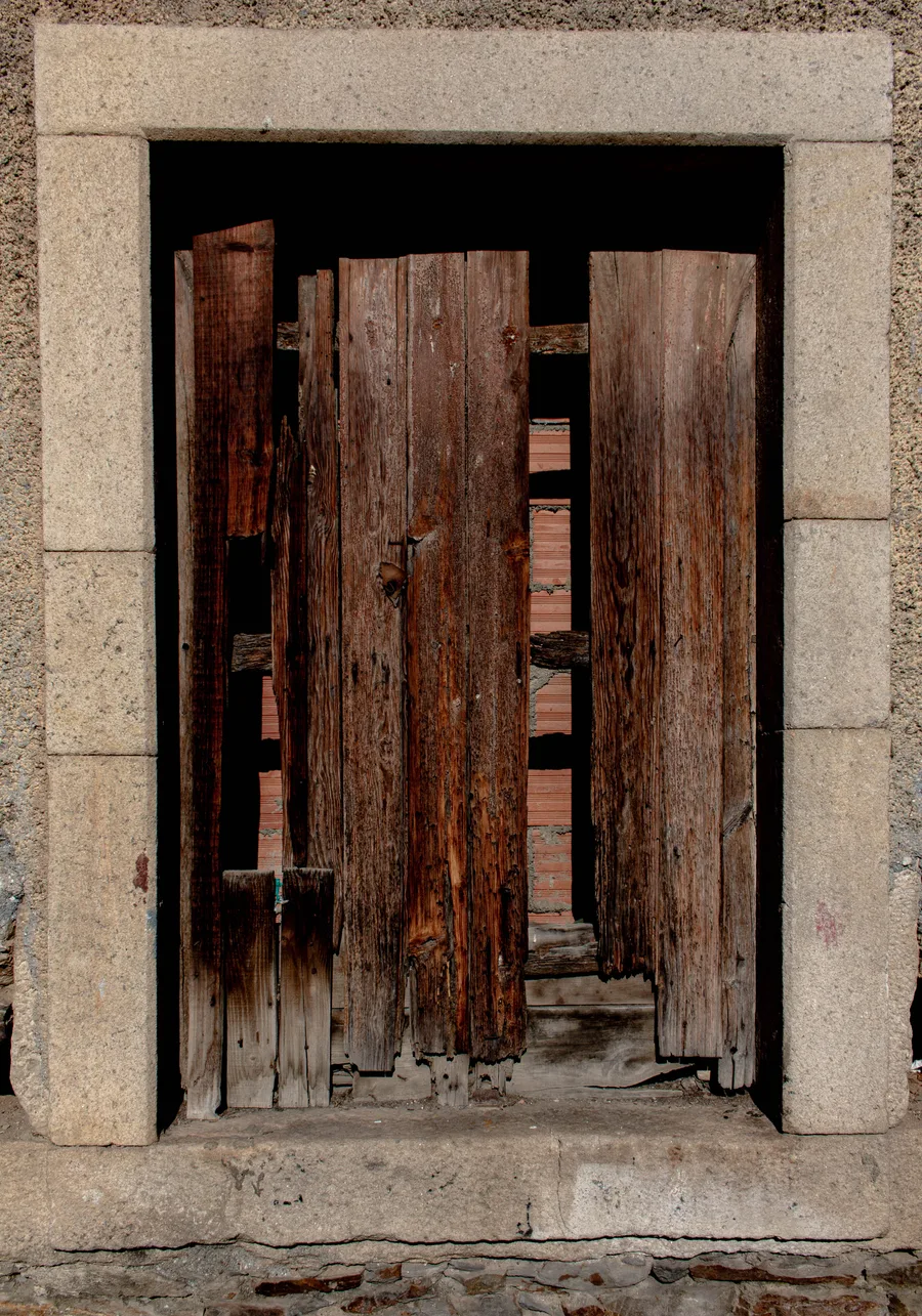 Weathered double wooden barn doors with brick showing between them