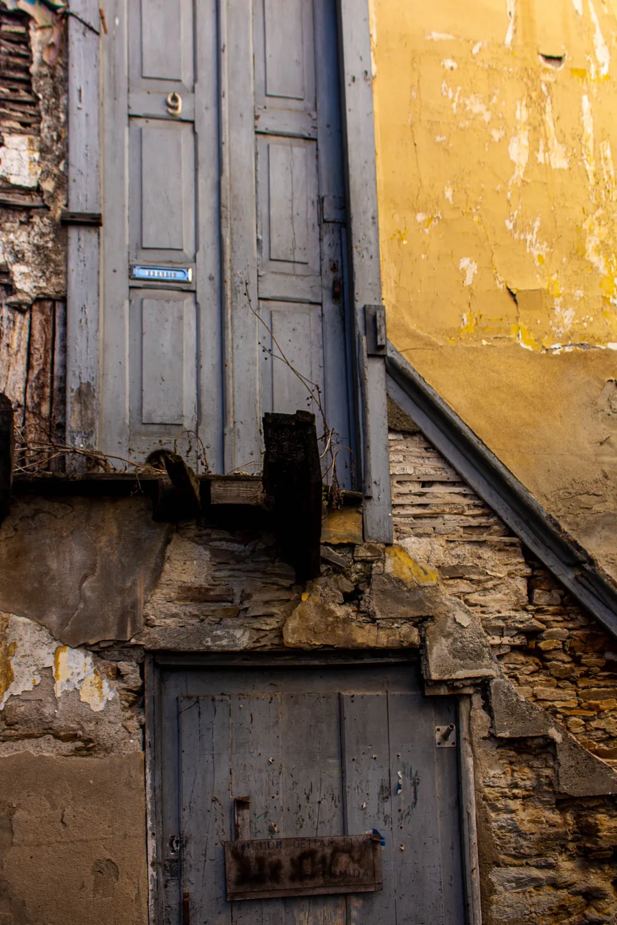 Blue-grey door in a mustard-yellow wall, angled composition
