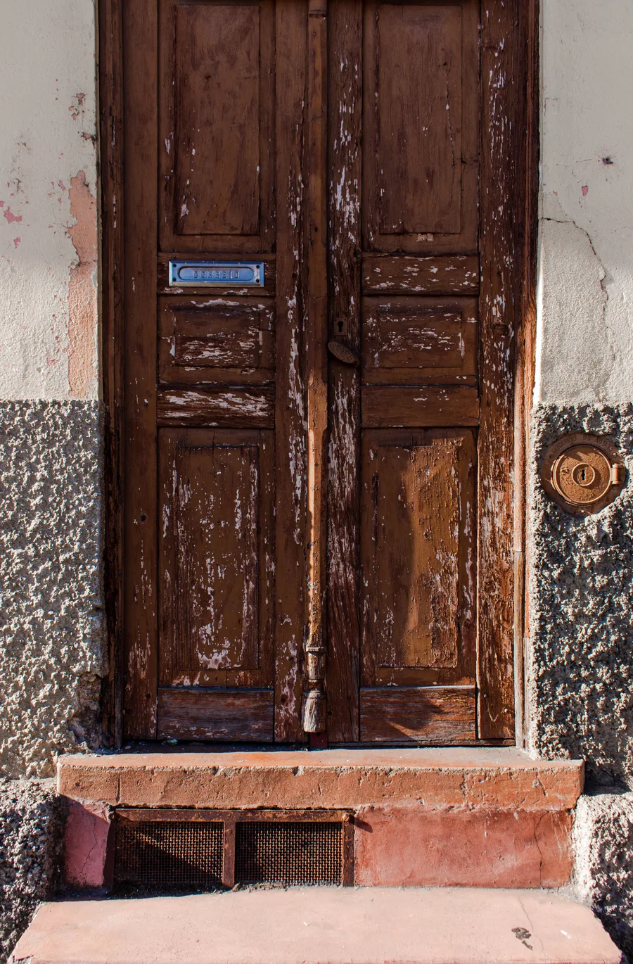 Brown wooden double door with a mailbox slot, symmetrical